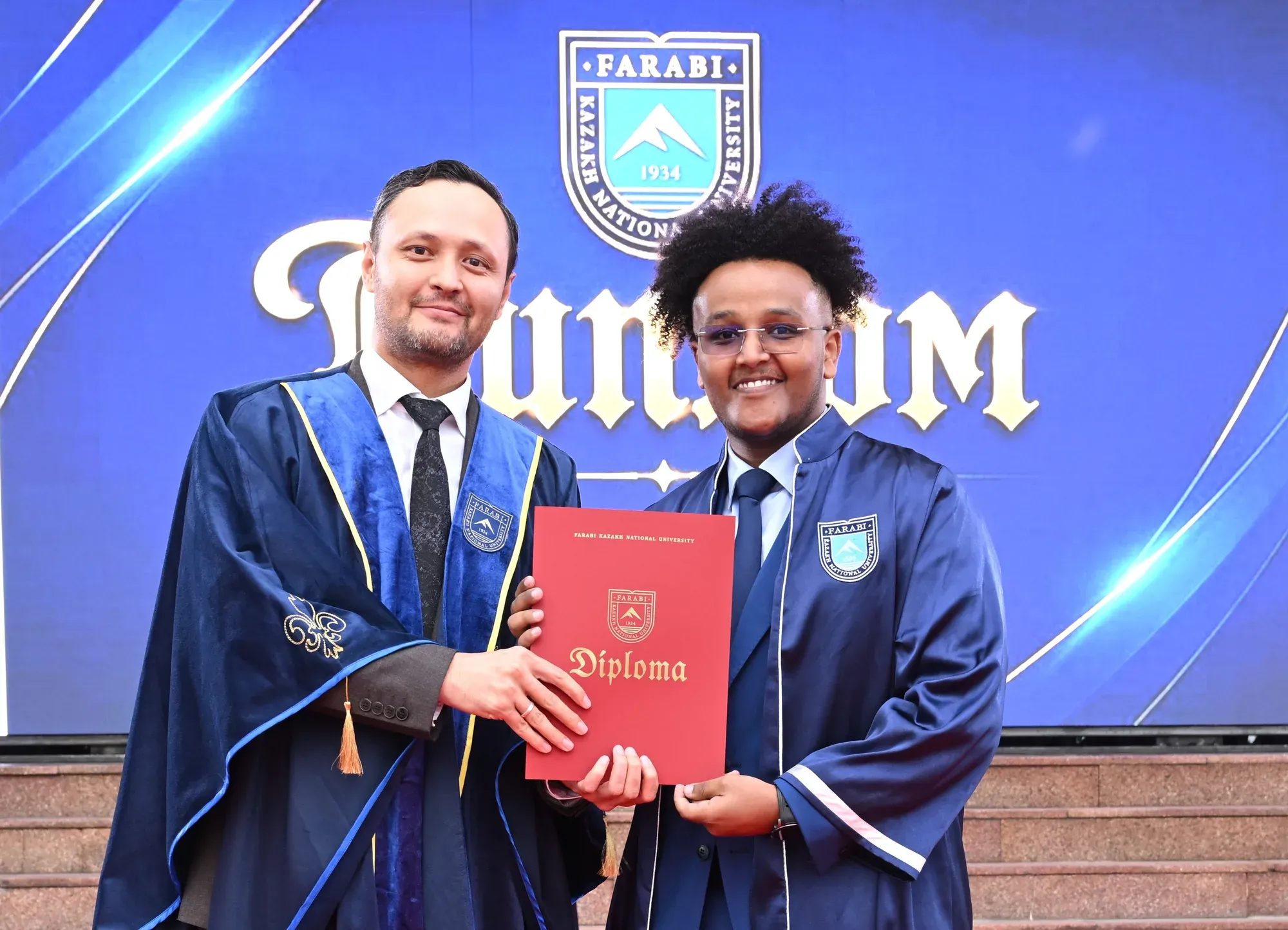 Samson and the dean holding his red diploma at his graduation with honours from KazNU.